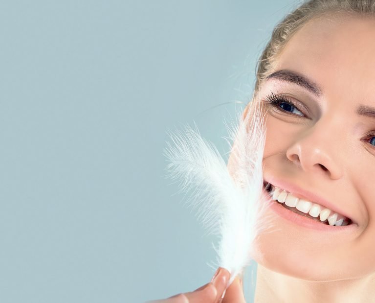 Portrait of attractive girl with closed eyes. beautiful woman with a white feather near her face. Face and body skin care concept, fresh clean shiny skin.