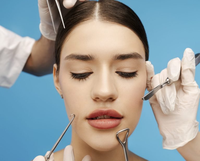 Young pretty woman receiving botox for wrinkles. Isolated on blue background. Beauty care, anti aging procedures, plastic surgery concept